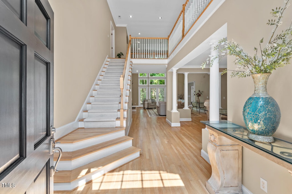 foyer featuring a high ceiling, decorative columns, and light hardwood / wood-style floors