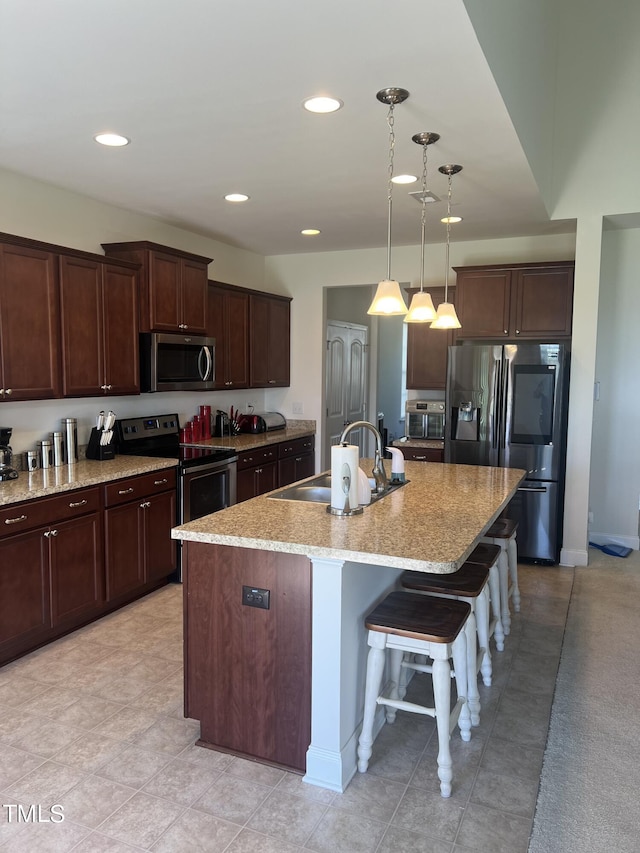 1565 Sage Treee Dr, Zebulon, NC 27597 - kitchen with a center island with sink, a kitchen bar, a sink, appliances with stainless steel finishes, and hanging light fixtures