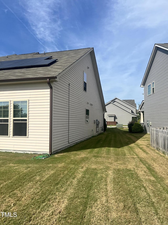 1565 Sage Treee Dr, Zebulon, NC 27597 - view of property exterior with a shingled roof, roof mounted solar panels, fence, and a yard