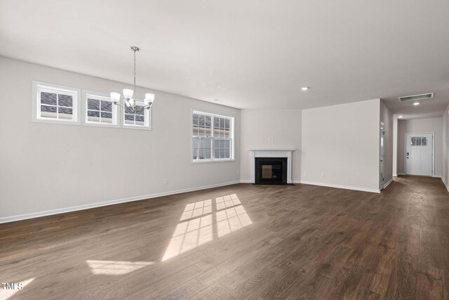 unfurnished living room with a chandelier and dark hardwood / wood-style floors