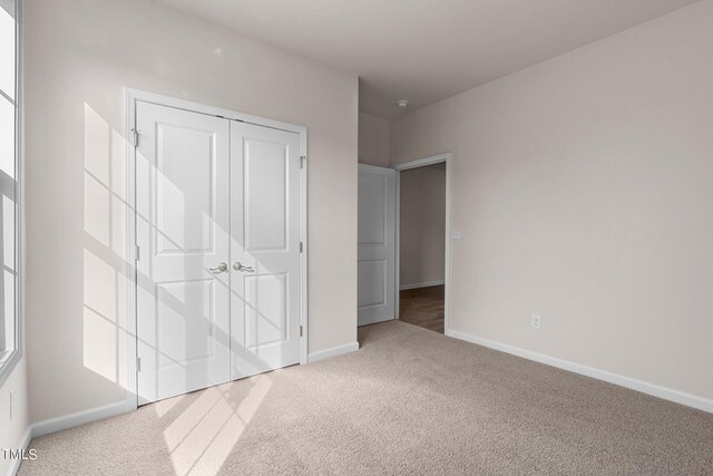 unfurnished bedroom featuring light colored carpet and a closet