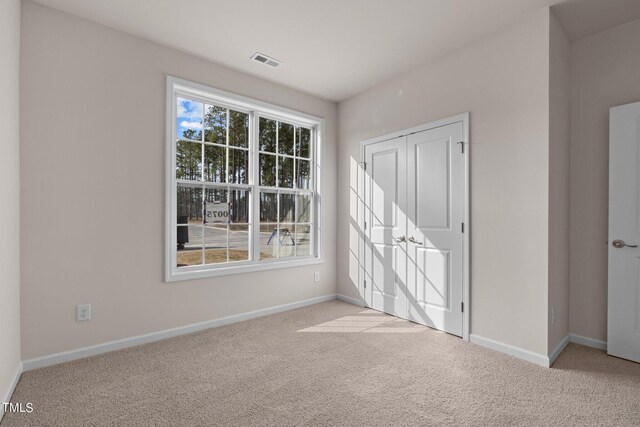 unfurnished bedroom featuring light colored carpet and a closet