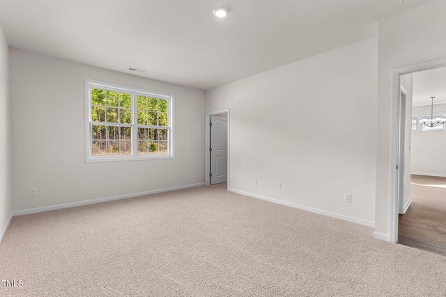 empty room with carpet flooring and a chandelier