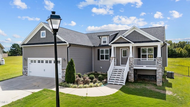 craftsman house featuring cooling unit, a porch, a garage, and a front yard