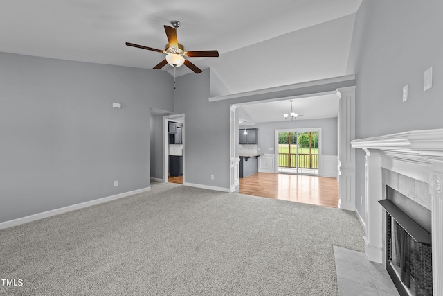 unfurnished living room featuring ceiling fan with notable chandelier, a fireplace, light carpet, and vaulted ceiling