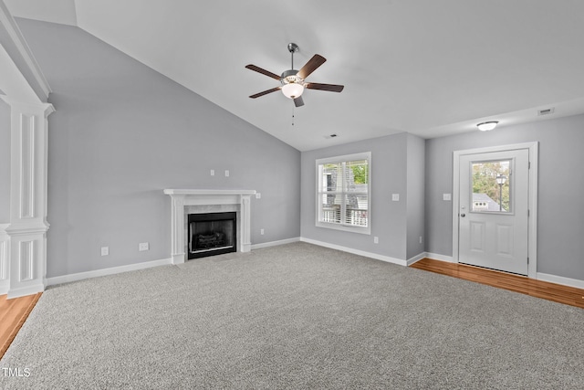 unfurnished living room with ceiling fan, a wealth of natural light, a high end fireplace, and vaulted ceiling