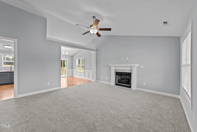 unfurnished living room featuring ceiling fan with notable chandelier, lofted ceiling, a high end fireplace, and carpet