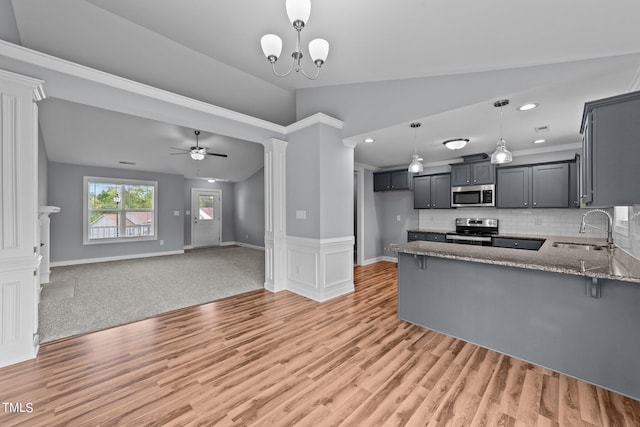 kitchen with light hardwood / wood-style flooring, ceiling fan with notable chandelier, light stone countertops, stainless steel appliances, and sink