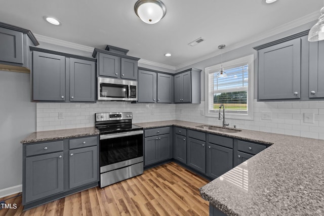 kitchen featuring light wood-type flooring, pendant lighting, stainless steel appliances, and sink