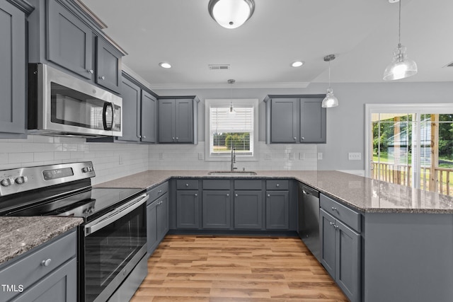 kitchen featuring plenty of natural light, stainless steel appliances, sink, and hanging light fixtures