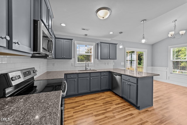 kitchen with lofted ceiling, appliances with stainless steel finishes, a wealth of natural light, and hanging light fixtures