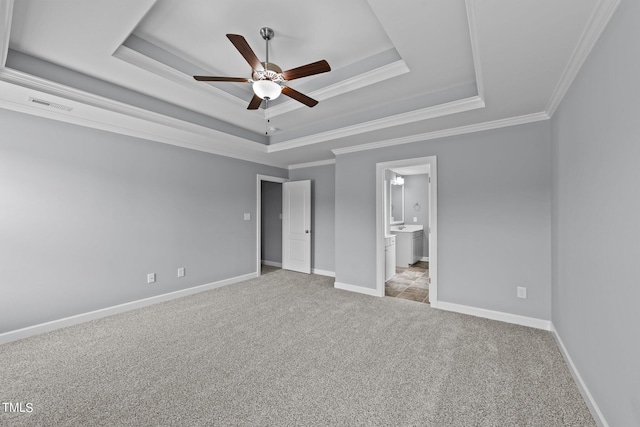 unfurnished bedroom featuring a tray ceiling, crown molding, light carpet, and ceiling fan