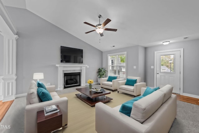 living room with light hardwood / wood-style flooring, ceiling fan, a fireplace, and vaulted ceiling