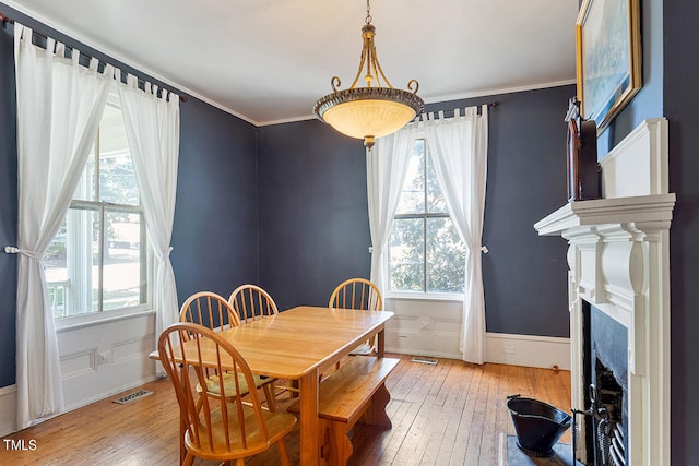 dining room with wood-type flooring, plenty of natural light, and crown molding