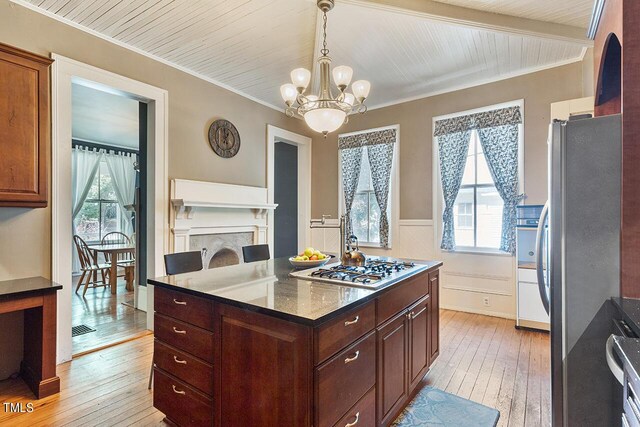 kitchen featuring a healthy amount of sunlight, stainless steel appliances, light wood-type flooring, and dark stone countertops