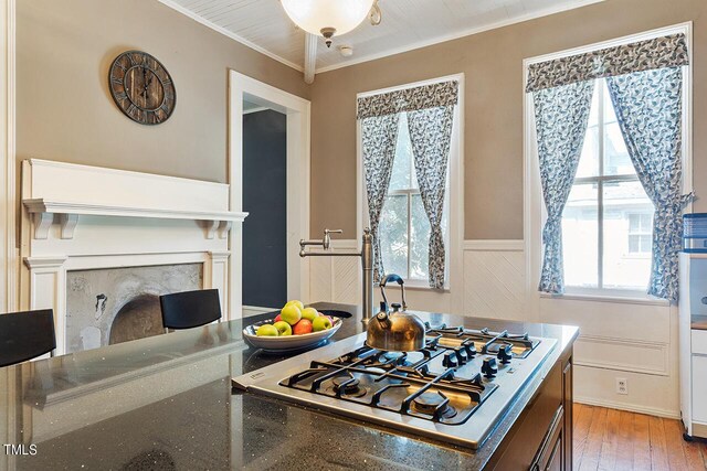 kitchen featuring crown molding, light hardwood / wood-style flooring, and stainless steel gas stovetop