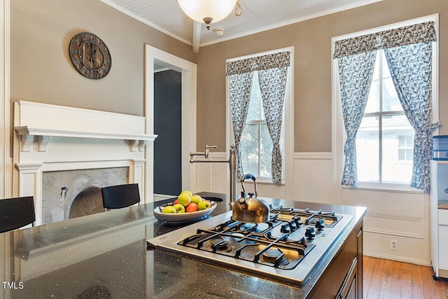 214 College St, Oxford, NC 27565 - kitchen featuring a wainscoted wall, a premium fireplace, stainless steel gas stovetop, light wood-style floors, and ornamental molding