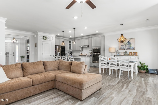 living area featuring light wood finished floors, a ceiling fan, and crown molding