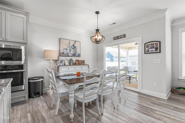 dining room with a chandelier, visible vents, ornamental molding, and light wood finished floors