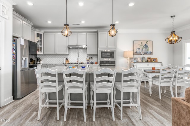 kitchen featuring tasteful backsplash, glass insert cabinets, appliances with stainless steel finishes, light stone counters, and ornamental molding