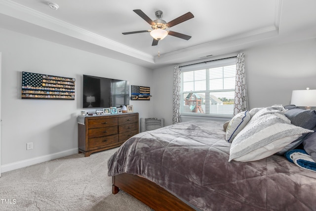 carpeted bedroom featuring baseboards, ceiling fan, a tray ceiling, and crown molding