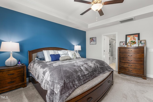 bedroom with a tray ceiling, crown molding, light colored carpet, visible vents, and ceiling fan