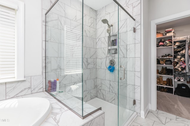 full bathroom featuring marble finish floor, a spacious closet, a garden tub, and a stall shower