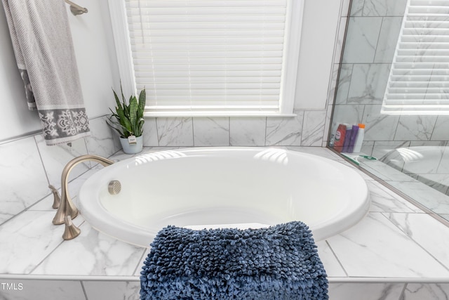 bathroom featuring marble finish floor and a bath