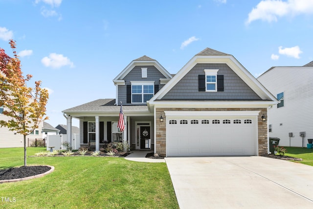 craftsman house with driveway, a front lawn, stone siding, and fence