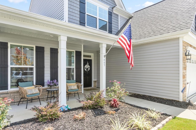 entrance to property featuring a shingled roof and covered porch