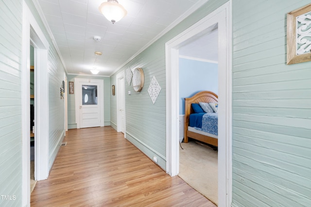 hall with ornamental molding and light hardwood / wood-style floors