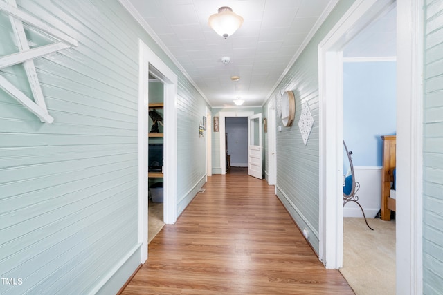 hall featuring ornamental molding, wood walls, and light hardwood / wood-style floors