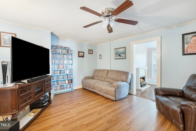 living room with a textured ceiling, ceiling fan, ornamental molding, and light hardwood / wood-style floors