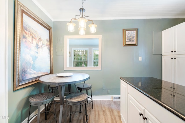 dining room with ornamental molding, a chandelier, and light hardwood / wood-style floors