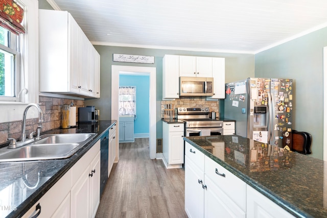 kitchen with appliances with stainless steel finishes, backsplash, white cabinetry, and sink