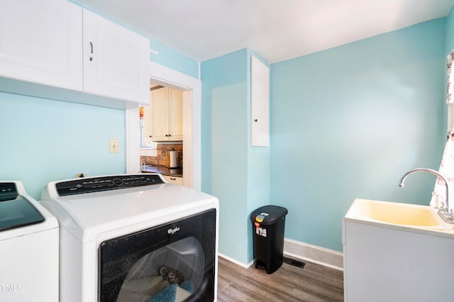 laundry area with hardwood / wood-style flooring, sink, cabinets, and washing machine and dryer