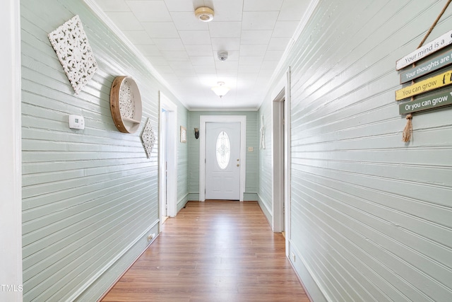 entryway with hardwood / wood-style floors, wooden walls, and crown molding