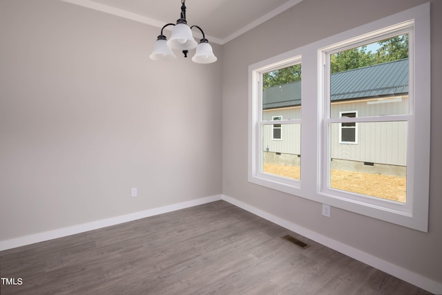 spare room featuring crown molding, a chandelier, plenty of natural light, and wood-type flooring