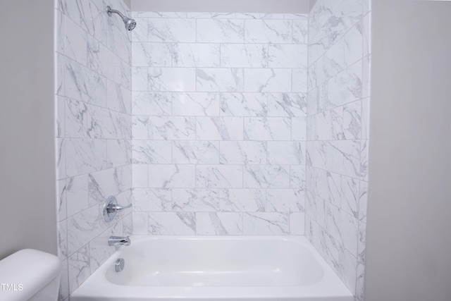 bathroom with tiled shower / bath combo and toilet