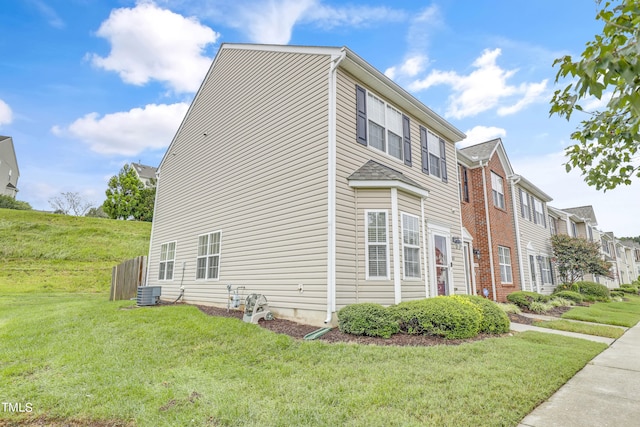 view of side of home with central AC and a yard