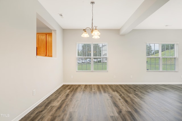 spare room with dark wood-type flooring, a notable chandelier, a healthy amount of sunlight, and beam ceiling