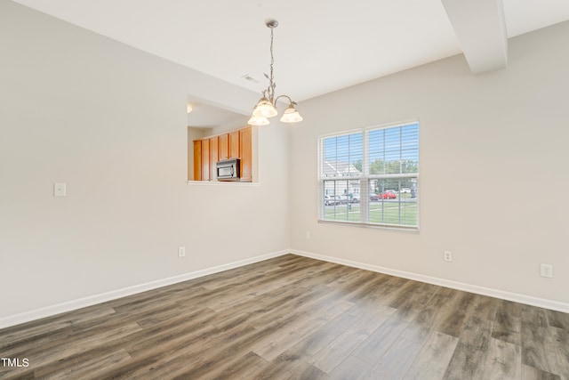 unfurnished dining area with dark wood-type flooring and an inviting chandelier