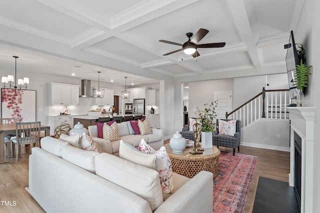 living room with coffered ceiling, beamed ceiling, crown molding, ceiling fan with notable chandelier, and light wood-type flooring