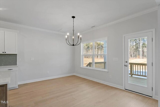 unfurnished dining area with ornamental molding, light wood-type flooring, and plenty of natural light