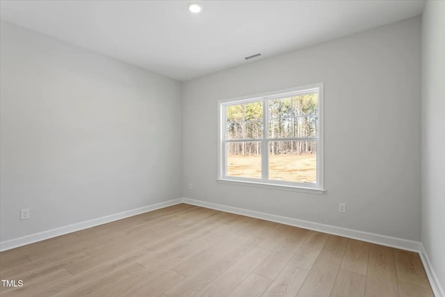 unfurnished room with baseboards, visible vents, and light wood finished floors