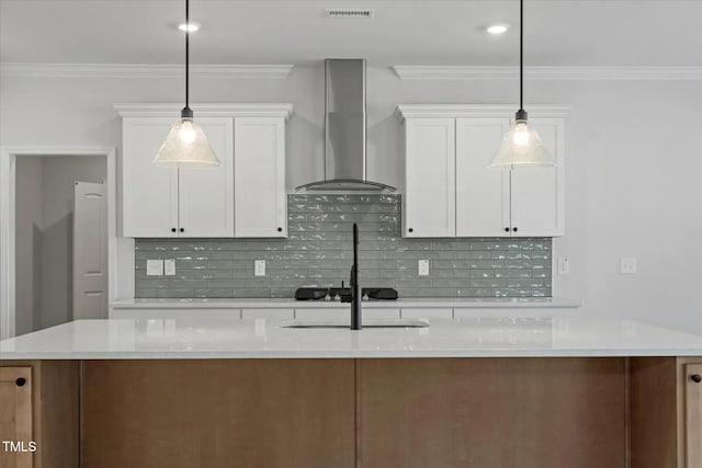 kitchen with pendant lighting, white cabinetry, a center island with sink, and wall chimney exhaust hood