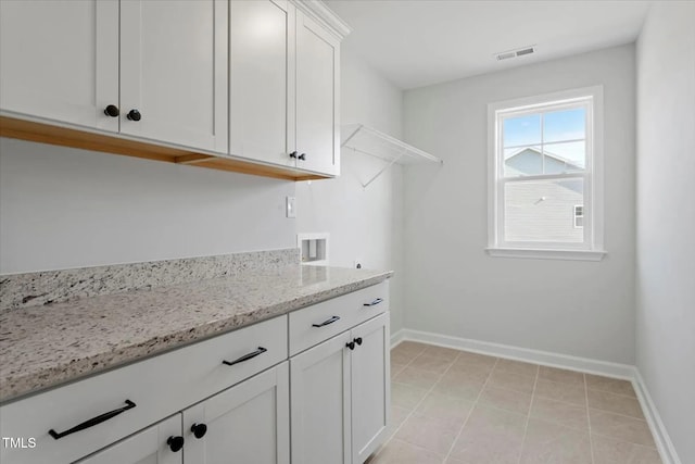 clothes washing area with visible vents, washer hookup, cabinet space, and baseboards
