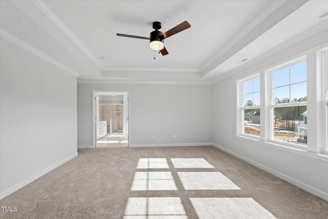 unfurnished room featuring light carpet, baseboards, ceiling fan, a tray ceiling, and crown molding