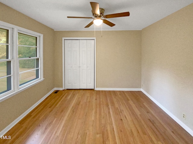 unfurnished bedroom with light wood-type flooring, a closet, and ceiling fan