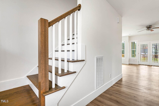 staircase with french doors, ceiling fan, and hardwood / wood-style flooring